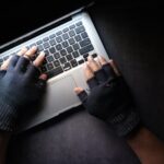 picture of person wearing gloves typing on a laptop