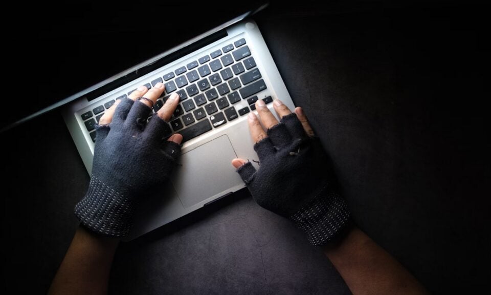 picture of person wearing gloves typing on a laptop