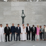 Tourism and business delegation group photo at a major Middle East museum in front of a large inscribed wall