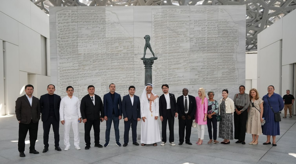 Tourism and business delegation group photo at a major Middle East museum in front of a large inscribed wall