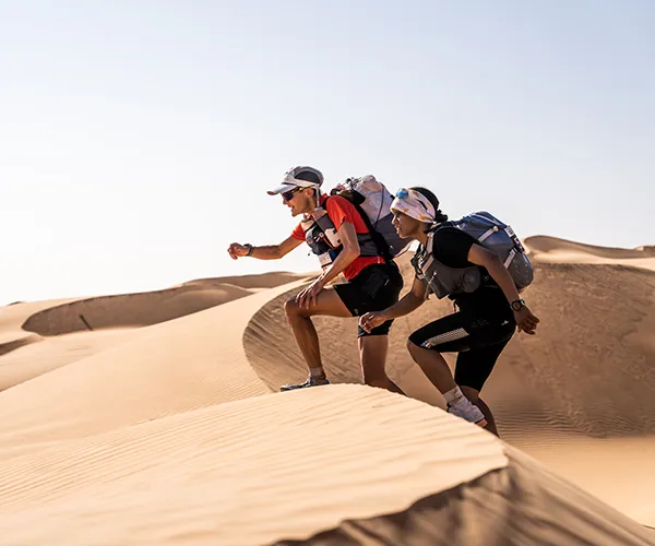 Two runners navigating sand dunes during the Oman Desert Marathon