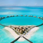 Aerial view of Nujuma Red Sea overwater villas arranged in a distinct circular pattern over turquoise water