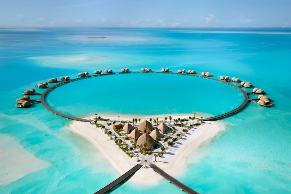 Aerial view of Nujuma Red Sea overwater villas arranged in a distinct circular pattern over turquoise water